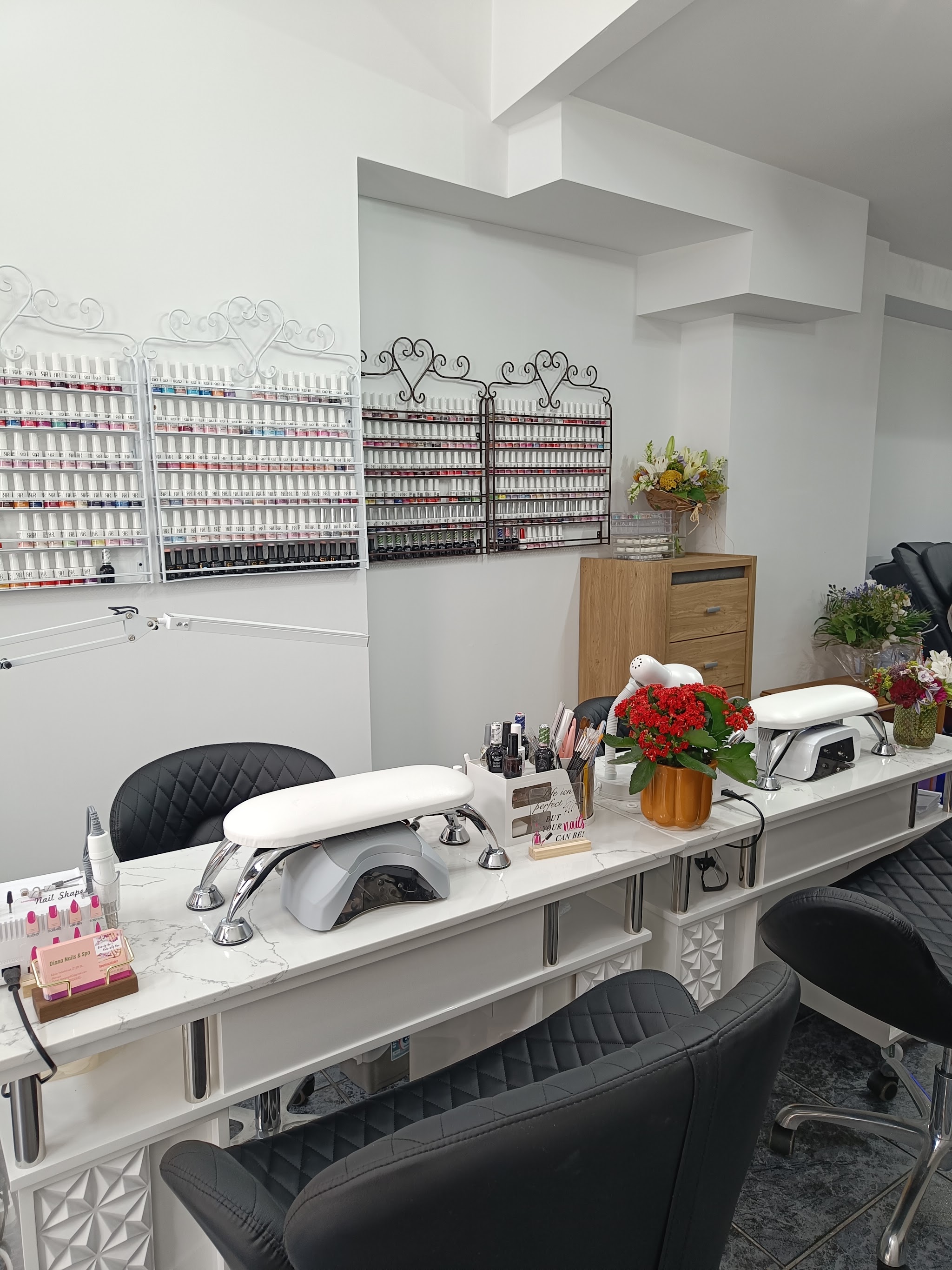 De salon: werkplekken met wit marmer, zwarte stoelen, nagellampen en een wand vol lakjes